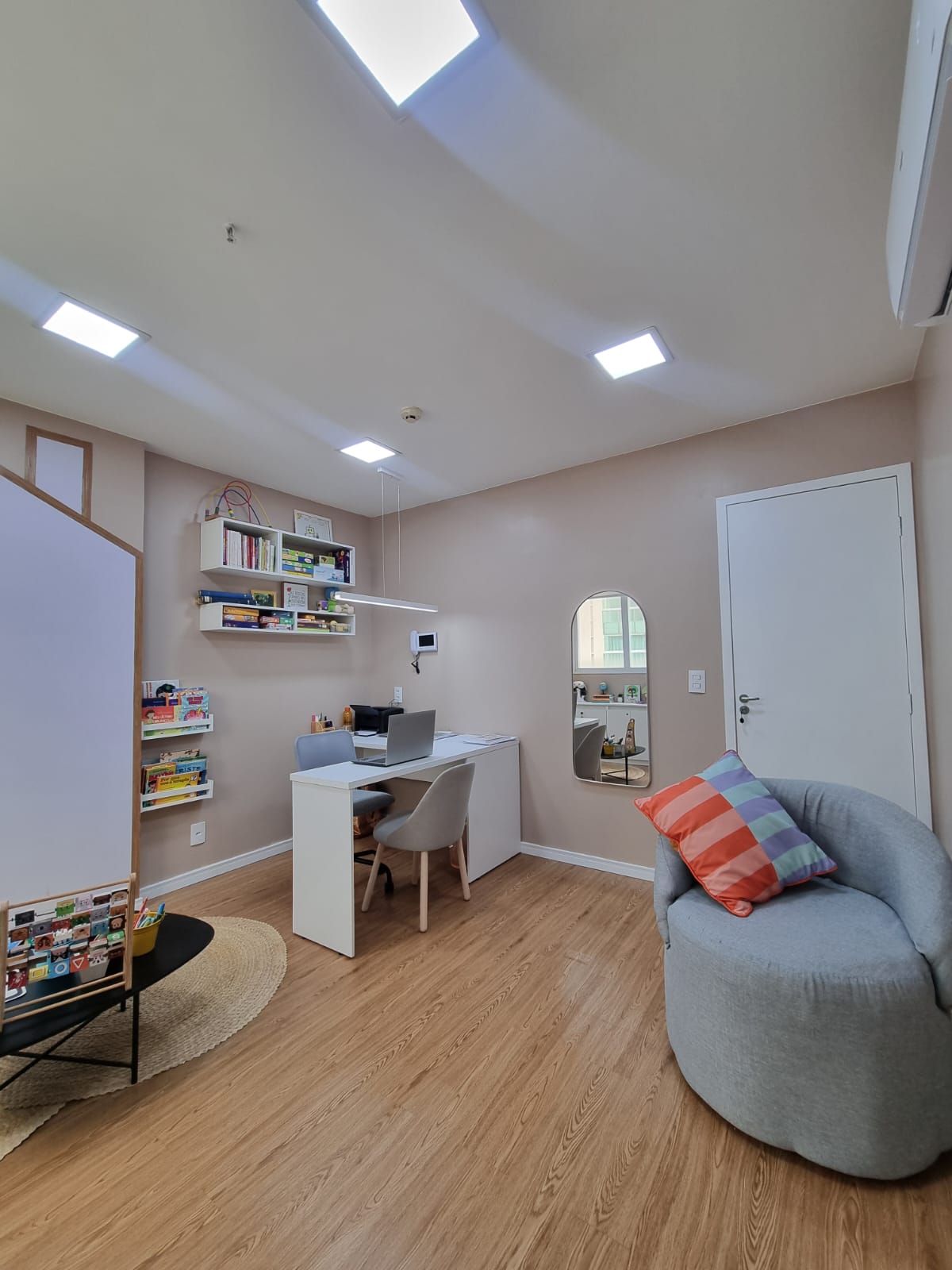 Sala de atendimento com mesa de trabalho, lousa em formato de casinha e poltrona