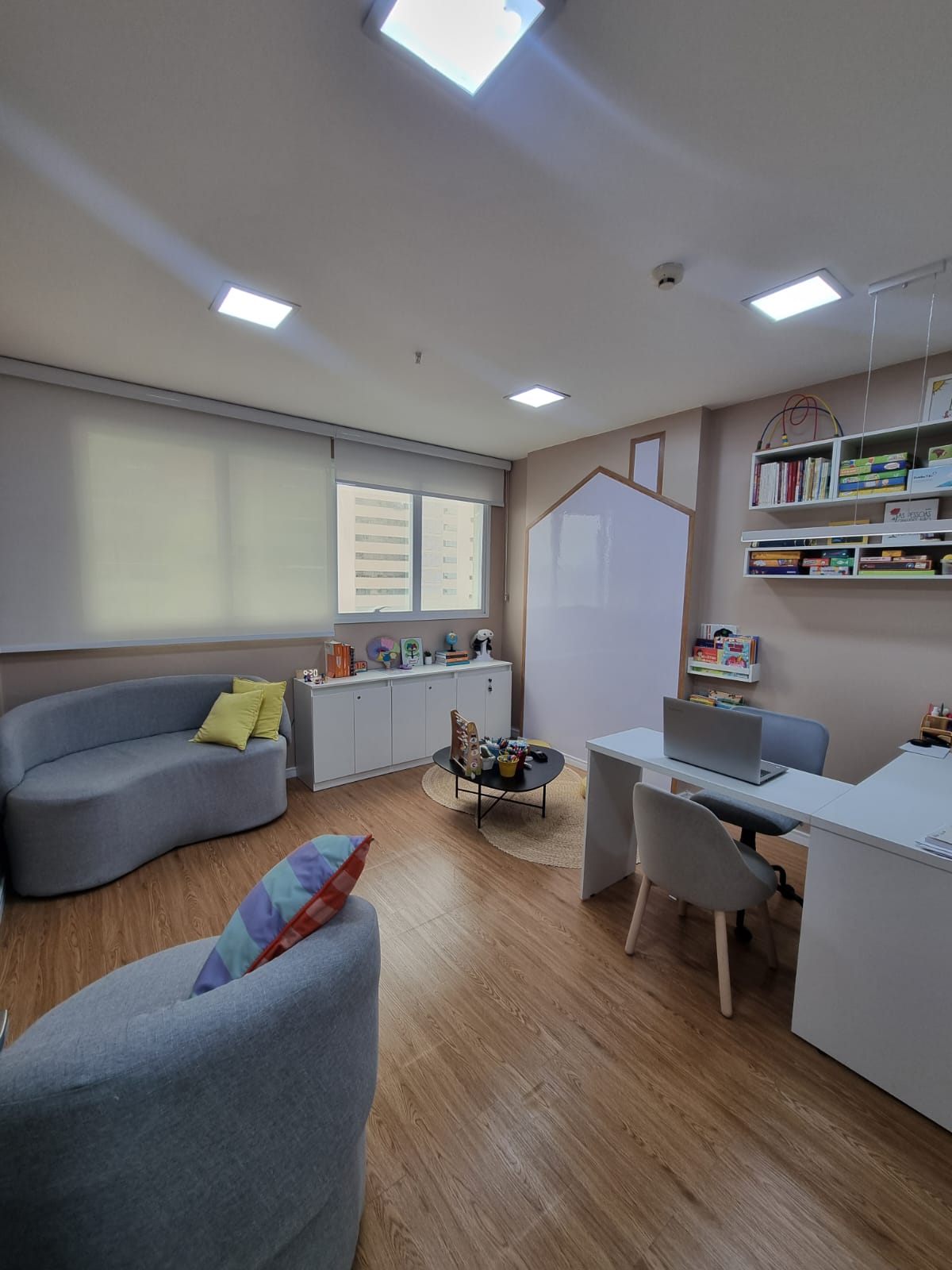 Sala de atendimento com sofá, janela e cantinho de brinquedos